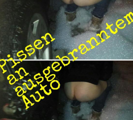 neben ausgebrantem Auto gepisst
